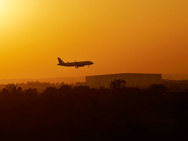 A plane landing from above the Boeing AirIndia MRO during sunset